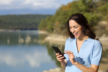 Happy woman laughing checking phone in mountain