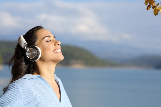 Happy woman meditating wearing headphones in a lake
