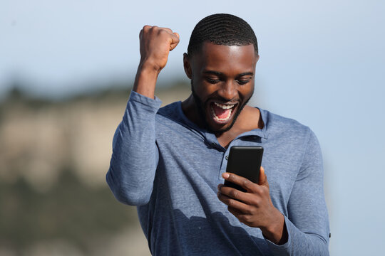 Man with black skin celebrating checking phone