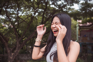 A hysterical young woman laughs uncontrollably. Reacting to a very funny joke. Copyspace on the left. Outdoor scene. - obrazy, fototapety, plakaty