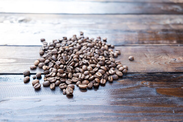 Roasted coffee grains on a wooden table close-up.