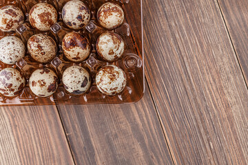 Group of quail eggs are put on clear tray on wooden table.