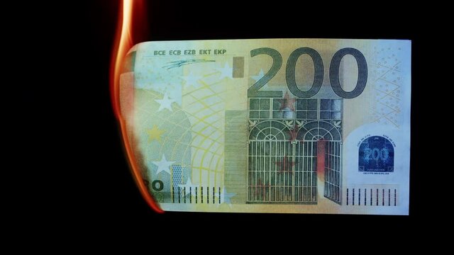 Burning of 200 euro banknote on black bacground close-up. Flame of fire from cash. Financial crisis and depressed economy. Paper money loss concept.