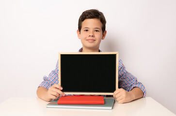 Student boy at his desk showing a board isolated over white background.