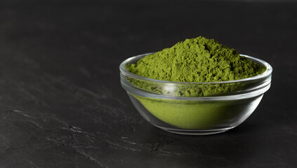Chlorella green powder in a bowl on a stone black background. Spirulina powder or barley powder. Superfood. Copy space.