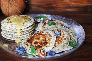 Pancakes with fresh raspberries, mint and jam on a black table with lonicera