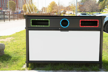 Close up of a recycling bin with a a blank billboard in a public park on a sunny autumn day. Copy...
