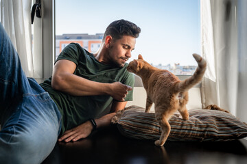 young man interacts with a brown tabby cat
