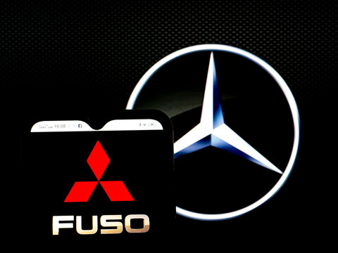 In This Photo Illustration, The Mitsubishi Fuso Truck And Bus Corporation Logo Is Seen Displayed On A Smartphone Screen With The Daimler AG Logo In The Background.