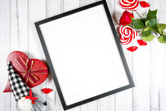 Art print frame product mockup. Valentine's Day farmhouse theme SVG craft product mockup styled with red roses, heart shaped gift, and buffalo plaid gnome against a white wood background. Flatlay.