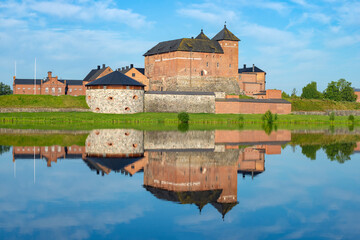 Naklejka na ściany i meble The ancient fortress of the city of Hameenlinna on the shore of Lake Vanayavesi with a reflection. Finland