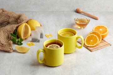 Two yellow cup of warming Honey Citron Tea with slices of orange and lemon.