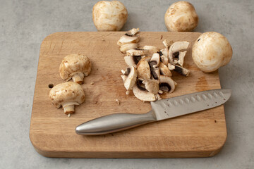 Raw delicious fresh white champignon on a wooden chopping board. Vegetarian recipe. Ingredients for cooking. Sliced portobello mushrooms on a light background.