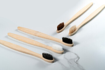 five bamboo toothbrushes on grey background.