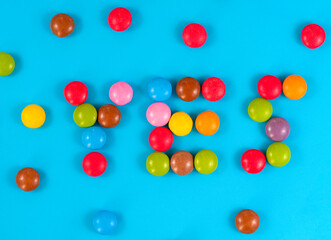 Multicolored round candies on blue background top view
