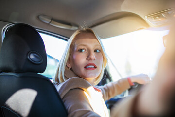 Woman in car indoor turning around looking at passengers in back seat idea taxi driver. Concept of...