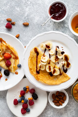 Crepes with banana slice, berries jam and chocolate sauce top view food