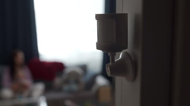 Smart home wireless motion sensor installed on the wall of the living room, motion detector used to detect activities like movement and control smart lights. High quality 4k footage