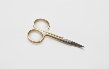 Small scissors. Steel nail scissors, gold hundle isolated on white.