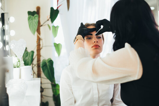 a girl in a beauty salon has an eyebrow lamination procedure, smears with white paste