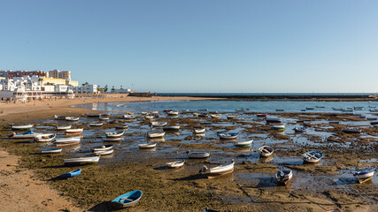 Boats docked in La Caleta beach in Cadiz Bay at low tide, Andalusia, Spain