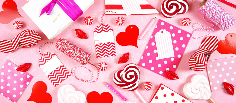 Happy Valentine's Day gift wrap theme on trend overhead with pink, red and white gifts, cards, tags and candy. Creative composition flat lay. Sized to fit popular social media and web banner.