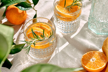 Summer refresh orange cocktail with ice, herb and ripe bio citrus fruits on linen tablecloth....
