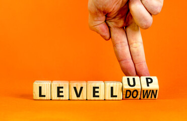 Level up or down symbol. Businessman turns cubes and changes concept words level down to level up. Beautiful orange table, orange background. Business and level up or down concept. Copy space.