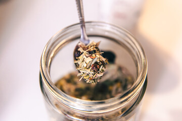 Close-up of a teaspoon and a jar of herbal tea.