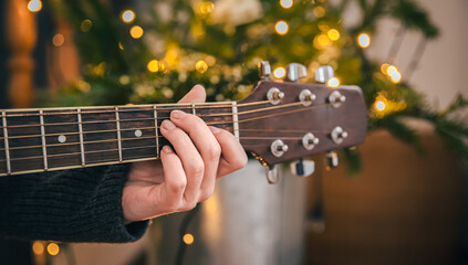 Close-up, female hands playing the guitar on a blurred background.