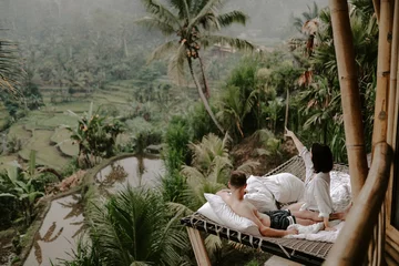 Abwaschbare Fototapete Bali Young travelling couple relaxing in the jungle resort hotel in Bali, Indonesia surrounded by rice fields, palm trees and lush green landscape