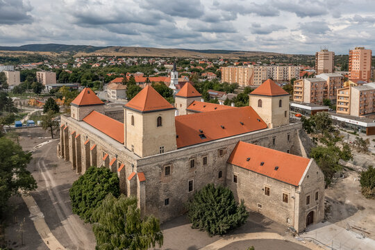 Aerial view of Varpalota Thury castle with newly renovated red orange roof, four rectangular towers in the middle of the former mining town with communist block houses in the background, modern vs old