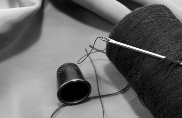 Vintage retro spool of thread on a black and white fabric background. Needle with thread