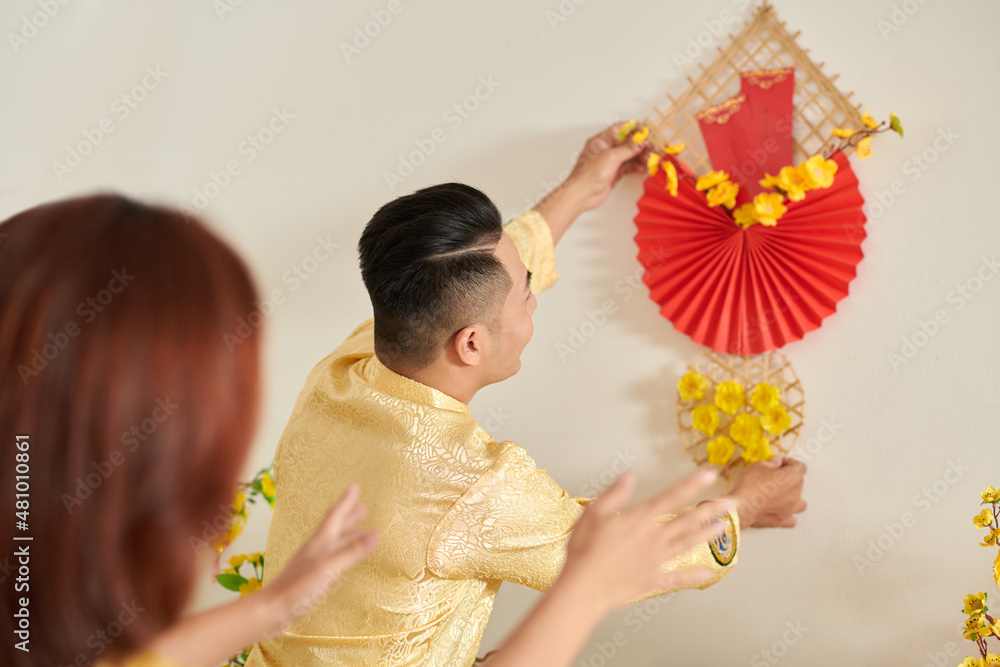 Poster Couple having wall decoration when preparing house for Lunar New Year celebration