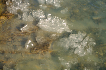 water flowing over rocks and ice in mountain river