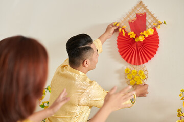 Couple having wall decoration when preparing house for Lunar New Year celebration