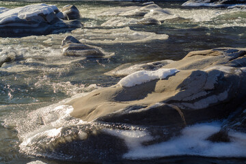 water flowing over rocks and ice in mountain river