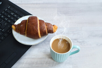 Cozy start to the working day: homemade cakes on the computer keyboard, a cup of hot coffee on a white table, space for text