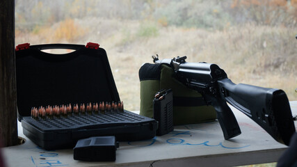 Kalashnikov assault rifle along with ammunition at the firing line of the shooting range