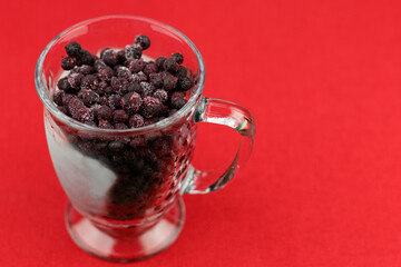 Frozen Wild Blueberries in a Glass Mug Close-up on Red Background