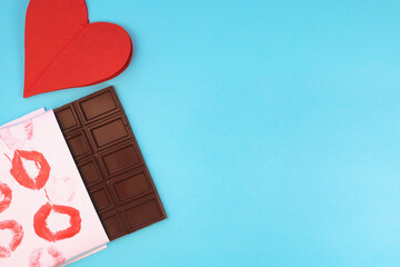 Chocolate bar wrapped in white paper with lipstick kiss prints. top view, copy space. Sweet tooth concept. Valentines day greeting card 