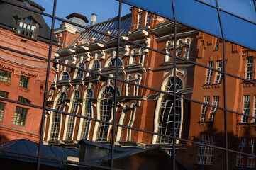 reflection of an old brick building in the glass of a modern building