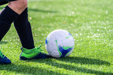 Close up view of a real amateur football player. Soccer player with a ball playing on the grass of...