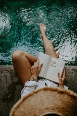 Young female relaxing by the pool in a modern and contemporary willa in Bali, Indonesia