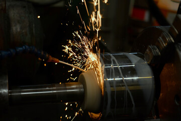 Roughing with a grinding abrasive wheel on a cylindrical grinder with sparks.