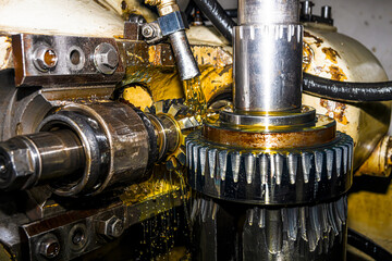 Making gears on a gear cutting machine. Machine oil cools the cutting process of the gear wheel with a modular cutter.