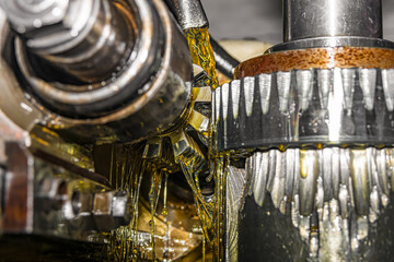 Making gears on a gear cutting machine. Machine oil cools the cutting process of the gear wheel...