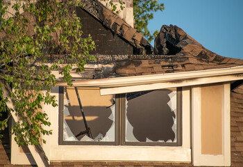 Close up of broken windows and burnt roof covering from a fire. 
