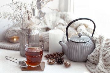 Cozy Scandinavian composition with teapot, a glass of tea, and decor details.