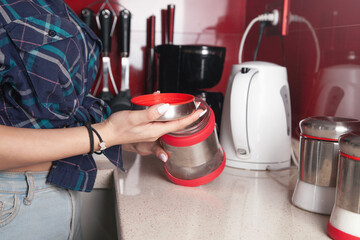 Woman holding glass jar of sugar in kitchen.